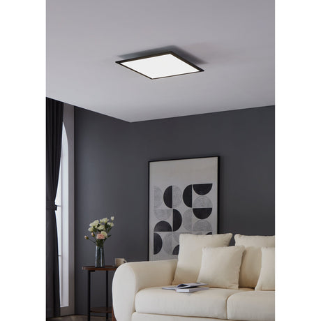 Frinarne LED Panel Light 45 x 45cm in black, a flush square ceiling fixture with slim aluminium frame, shown in a dark grey living room above a cream sofa.