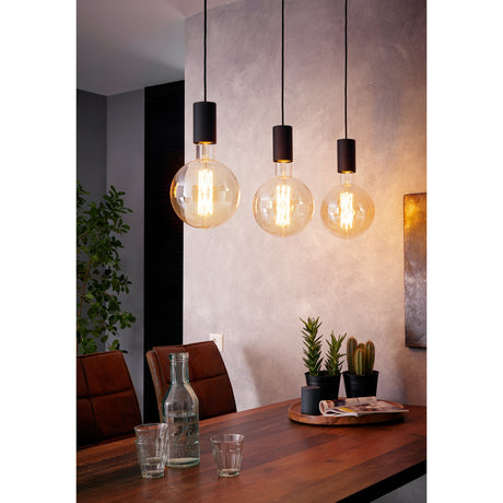 Frosvette Linear Pendant Light in black steel with three cylindrical holders on black cords, shown with globe bulbs above a dining table.