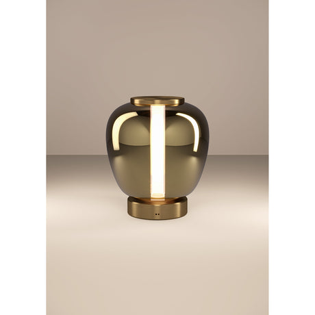 Fruitera LED Table Lamp in Brushed Brass, a vase-shaped mirrored glass body with brass cap and base, glowing warm vertical light strips, on a plain light background.