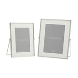 Two rectangular photo frames with slim silver edges and white mounts, in 4x6in and 5x7in sizes, each on a silver strut stand against a plain white background.