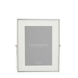 Rectangular photo frame with slim silver edge, white mount border, and fold-out strut stand, holding a 5x7in print on a plain white background.
