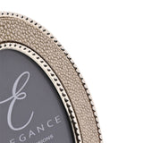 Close-up of an oval photo frame with a cream faux shagreen textured border edged by silver-tone beading, set against a plain white background.