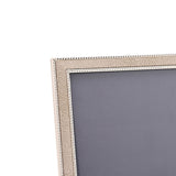 Close-up of a rectangular photo frame corner with champagne faux shagreen texture, silver-plated metal edges, and beaded trim, shown against a plain white background.