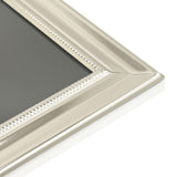 Close-up of a rectangular silverplated photo frame corner showing stepped moulding and a fine beaded border, with high-polish silver finish, on a plain white background.