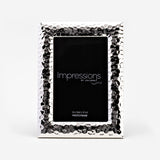 Textured freestanding silverplated photo frame with hammered dimpled border and smooth bevelled edge, holding a 4"x6" rectangular print, shown on a plain white background.
