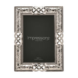 Rectangular silver metal photo frame with Celtic knot and scrollwork border, holding a 4x6in print, shown on a white background.