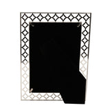 Rectangular silver-plated metal photo frame with an openwork lattice border of linked four-petal shapes, shown from the back with an easel stand, holding a 6 x 4in print, on a plain white background.