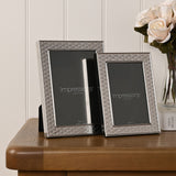 Two silverplated Art Deco scallop-pattern photo frames, 5x7in and 4x6in, displayed on a wooden table beside white roses.