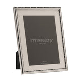 Silver metal photo frame with a criss cross lattice pattern border and white mount, holding a 5x7in placeholder image, shown at an angle on a plain white background.