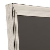 Close-up of a rectangular freestanding photo frame in silverplated metal, showing the moulded, layered profile at the corner against a plain white background.