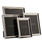 Four freestanding rectangular photo frames in silverplated metal with moulded stepped borders, shown in varying sizes on a plain white background.
