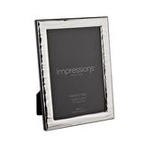 Rectangular silver-plated photo frame with a narrow rippled wave border, displayed at an angle on a plain white background, holding a 4 x 6in print.