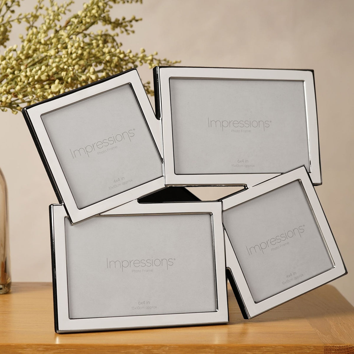 Overlapping multi-aperture photo frame in shiny silver metal, with four tilted openings—two square, two landscape—displayed on a wooden surface.