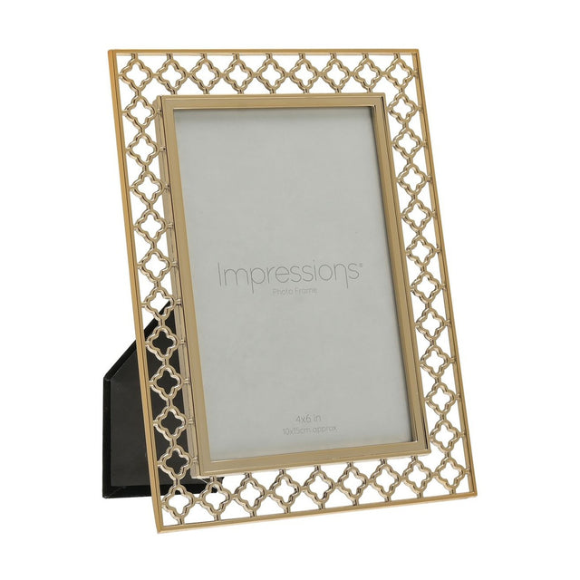 Gold quatrefoil lattice cut metal photo frame, 6 x 4in, rectangular with easel back stand, shown at an angle on a plain white background.