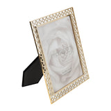 Gold lattice cut metal photo frame, 10 x 8in, with quatrefoil cut-out border and stand, shown at an angle on a white background with a rose print inside.