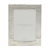 Rectangular silver-plated photo frame with a rippling, ridged texture across the border, holding a 7 x 5in print, shown on a plain white background.
