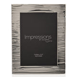Rectangular silver-plated photo frame with rippled, ridged texture and bright polished finish, holding a 7 x 5in portrait print on a white background.