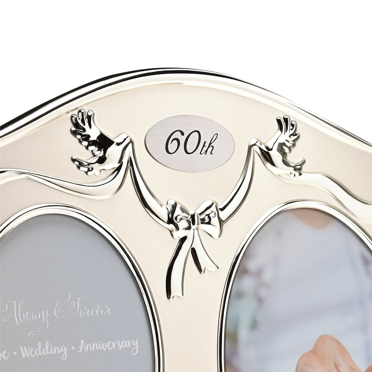 Close-up of the silverplated double photo frame's arched top, showing a "60th" oval plaque, dove and ribbon bow details, and two-tone silver finish.