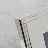 Close-up of the Gift Boxed Silverplated Rib Edge Metal Photo Frame corner, showing stepped ribbed border in polished silver finish against a marble-effect background.