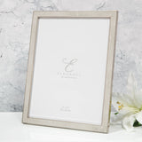 Rectangular faux shagreen photo frame in cream with a slim silver-plated metal edge and rear strut, shown on a white surface against a marble background.