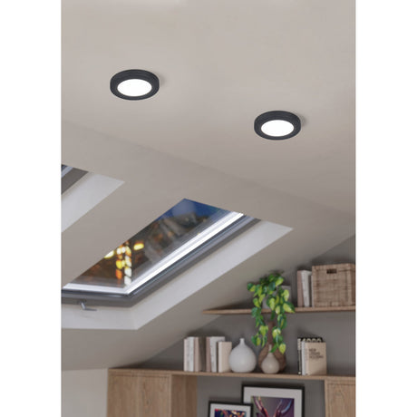 Fueva Flex LED downlights in black aluminium with round white diffusers, recessed into a sloped ceiling above a shelving unit near a skylight.