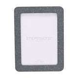 Speckled rounded wooden photo frame in grey with white flecks, holding a 7 x 5in print, shown on a plain white background.