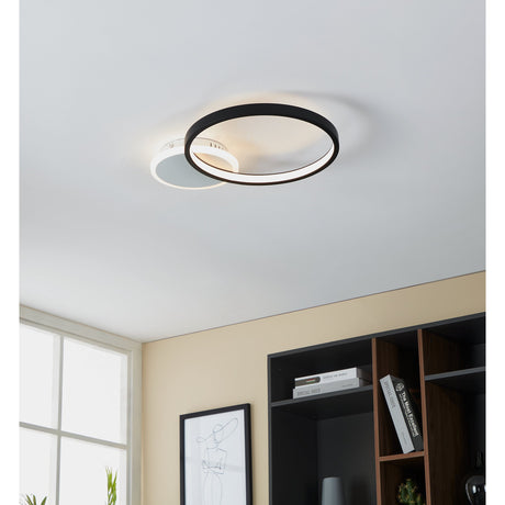 Gafares LED flush ceiling light in black and white, an asymmetric ring design with glowing inner diffuser, shown mounted on a white ceiling above a bookshelf.