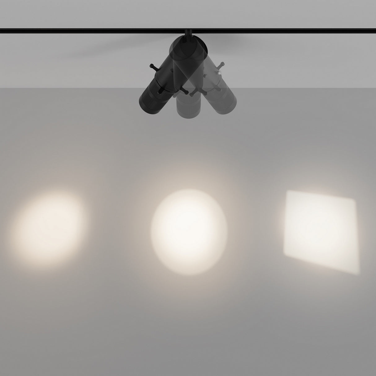 The Gala CCT Dimmable LED Magnetic Exility Track Spotlight 10W 2700-6000K in black features three adjustable lamps that project unique shapes—two round and one square—onto a gray surface. CCT dimmable technology allows varying brightness and clarity of the light beams.