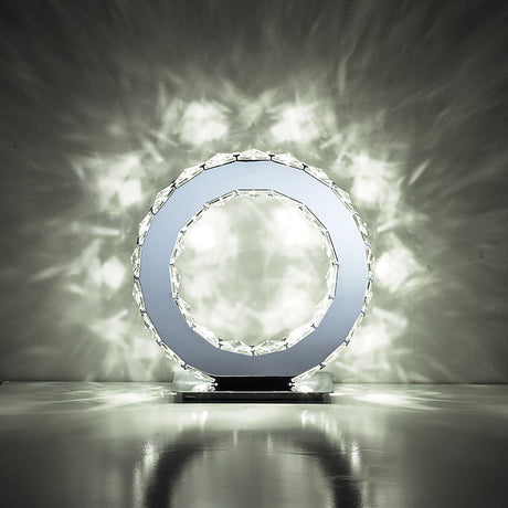 The Galaxy LED Crystal Round Table Lamp 10W 6000K in polished chrome features a crystal-like outer ring that casts bright, decorative light patterns on walls and surfaces, adding a sparkling effect to any dark room.