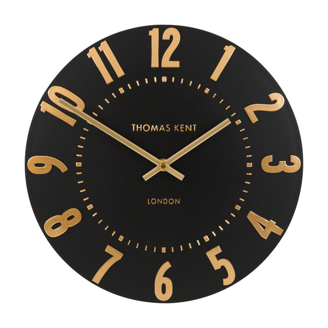 Gallery Direct Mulvorne Wall Clock with a matt black dial, raised gold-tone Arabic numerals and slim brass baton hands, on a white background.