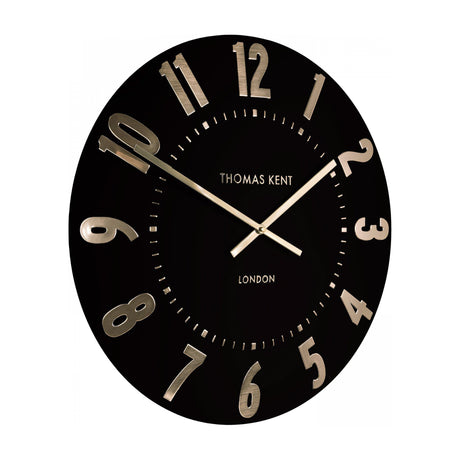 Gallery Direct Mulvorne Wall Clock with a matt black dial, raised gold-tone Arabic numerals and slim brass baton hands, on a white background.