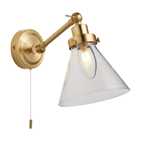 Gallery Direct Farvane bathroom wall light in satin brass with adjustable arm, clear glass cone shade and pull cord switch on a white background.