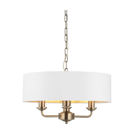 Gallery Direct Clervorne 3 light pendant with white fabric drum shade, gold-toned inner lining and antique brass three-arm frame on chain suspension.