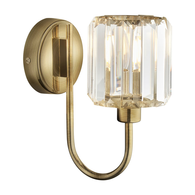 Gallery Direct Veranelle wall light with curved antique brass arm and faceted crystal glass shade on a white background.