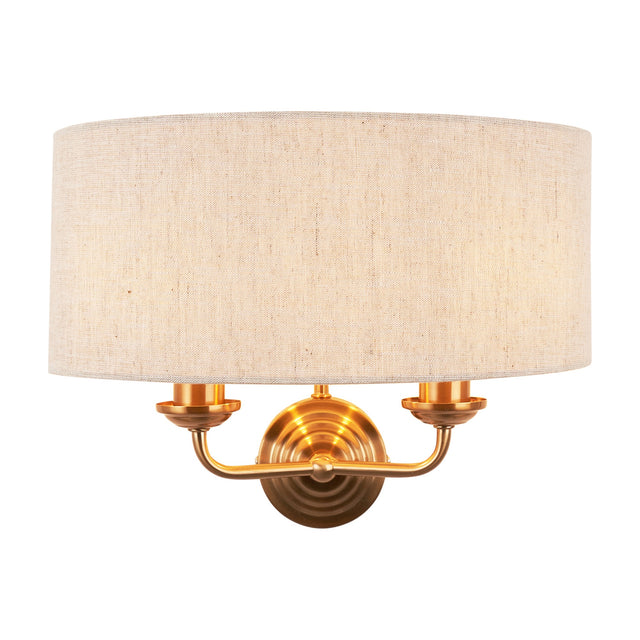 Gallery Direct Clervorne 2 Light Wall Light with brushed brass twin-arm sconce and half-drum natural fabric shade on a white background.