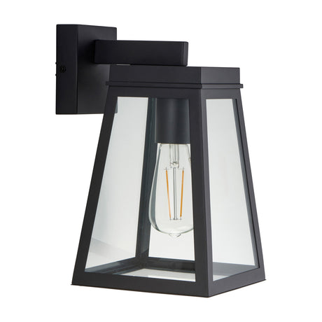 Gallery Direct Lyverna outdoor wall light in textured black with tapered lantern shape, clear glass panels and exposed filament bulb on a plain background.