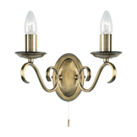 Gallery Direct Delwen twin wall light in antique brass with scrolled arms, oval backplate, two candle bulbs and pull-cord switch on a white background.