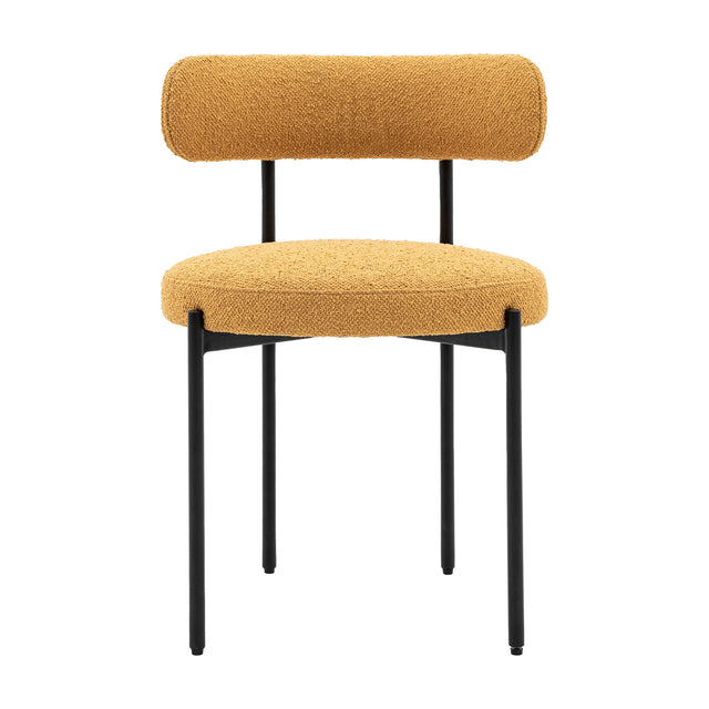 Gallery Direct Avelenne ochre bouclé dining chair with rounded bolster back, padded seat and slim black iron legs, shown on a plain white background.