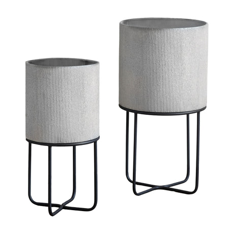 Gallery Direct Edvelle set of two ribbed grey metal cylindrical planters on slim black iron four-leg stands, taller and shorter pair on a white background.