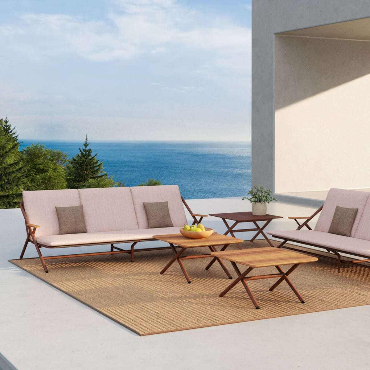 Garda 3 Seater Garden Sofa Cushion Set in pink fabric with brown accent cushions, fitted to a rust-finish aluminium frame sofa on an outdoor patio with sea view.