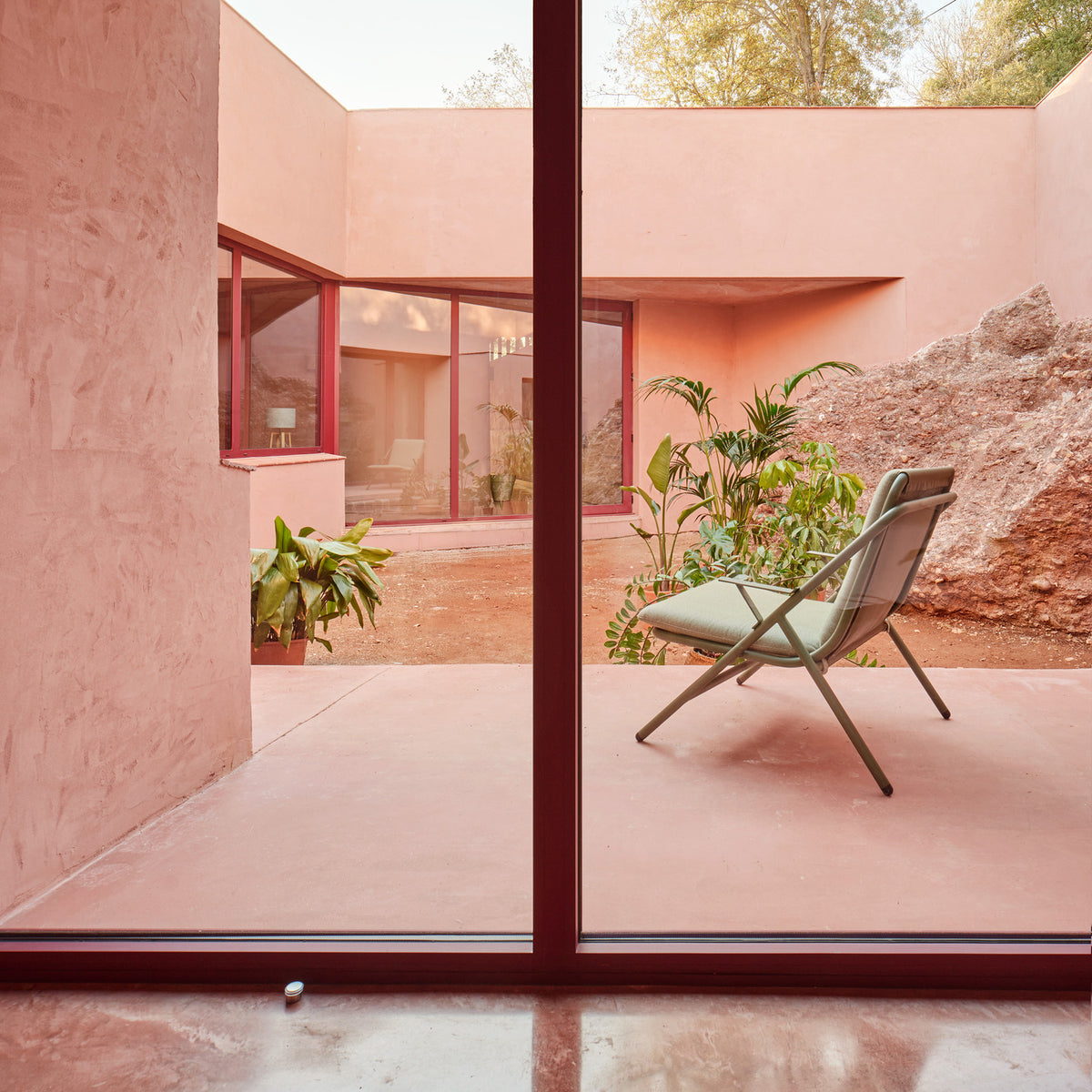 Garda High Back Garden Armchair Cushion Set in sage green fabric fitted to an aluminium folding frame chair on a pink-toned outdoor patio.