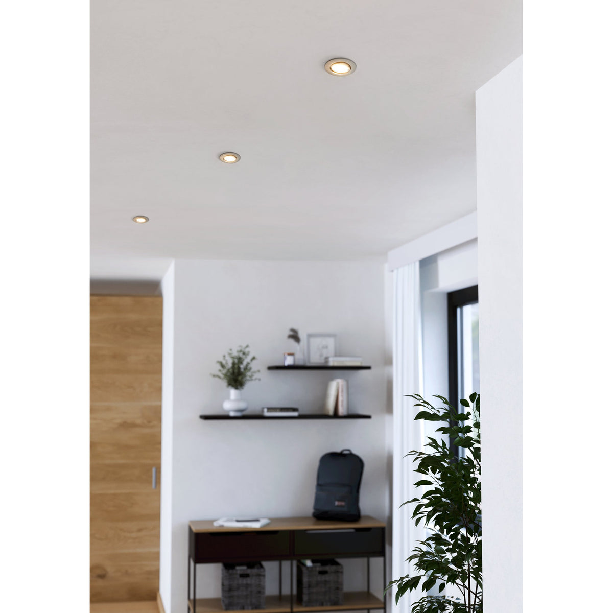 Gedrez LED Downlight Set of 3 in satin nickel shown recessed in a white hallway ceiling, illuminating a nearby shelving and console area.