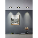 Gedrez LED Downlight Set of 5 in black, three round recessed ceiling fixtures shown installed, casting warm white light down a grey wall above framed artwork.