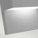 Close-up of the Geneve Outdoor 1 Light Wall Lantern in silver, featuring a modern, square-shaped design crafted from die-cast aluminium. The lantern is slightly angled, highlighting its smooth surface and bright white illumination emanating from within. It exudes elegance against a soft gray background, making it ideal for outdoor lighting.