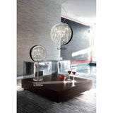 Modern living room with a large wooden coffee table, two glasses of red wine, and striking crystal and metal light fixtures—including the modern statement lamp IL30233 on the ceiling and the Geo Crystal 7 Light Table Lamp - Polished Chrome (IL30234) on the table.
