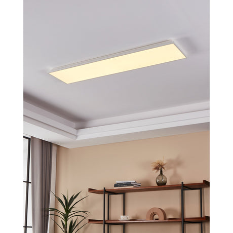 Gevette Smart LED Panel Light 120 x 30cm in white, a slim rectangular ceiling fixture with a white aluminium body, shown recessed into a coved ceiling emitting warm white light above a shelving unit.