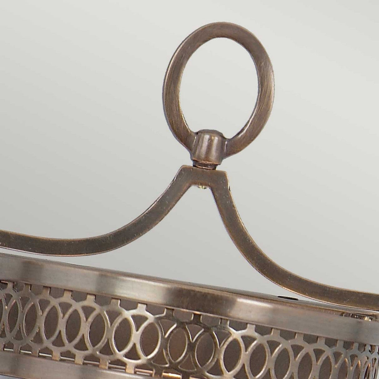 A detailed view of the Guildhall 1 Light Wall Light – Dark Bronze showcases its Georgian-inspired design, highlighted by a circular loop at the top and intricate patterns below. Its vintage lantern shape and dark bronze finish enhance its symmetry and smooth polish, making it a striking wall light accent.