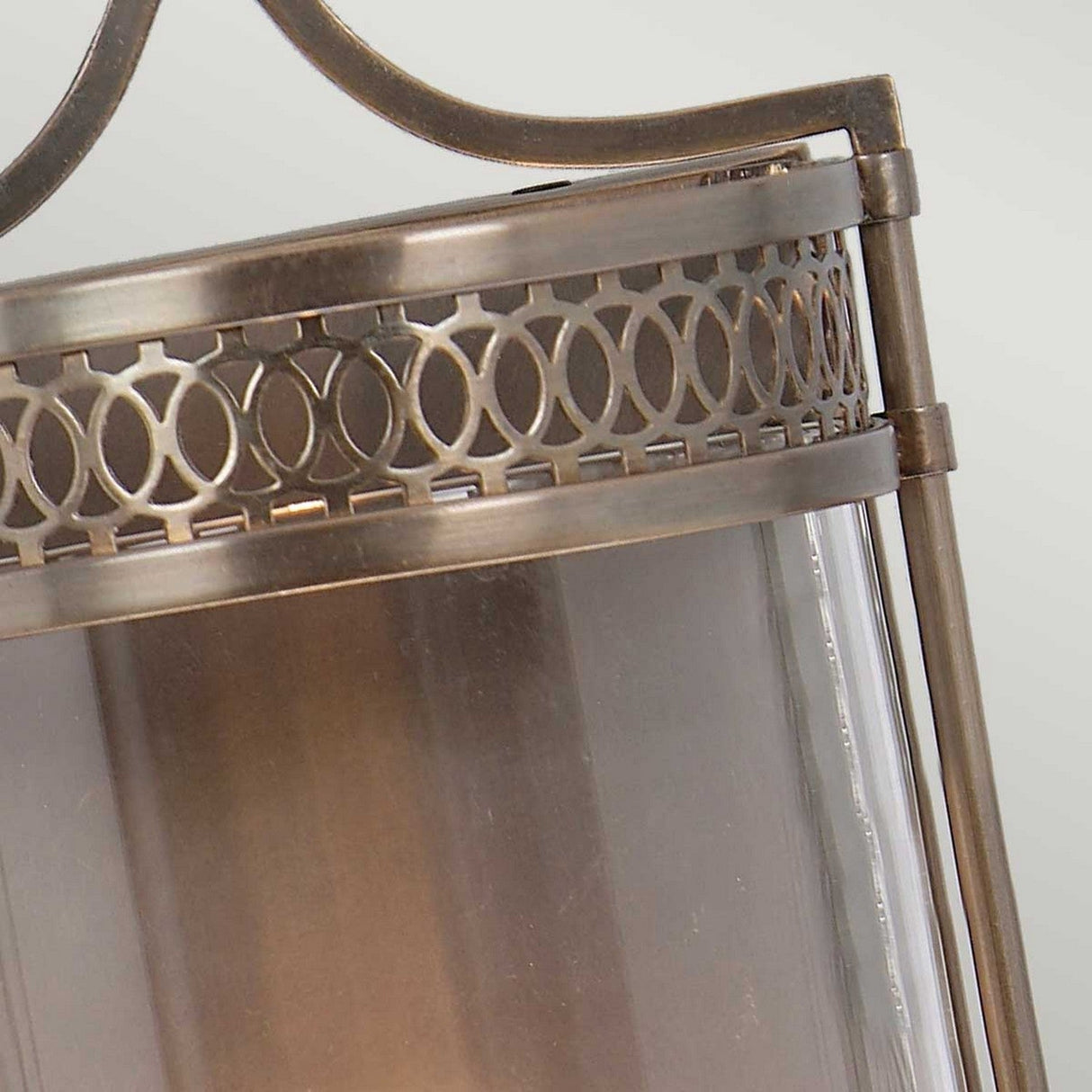 The Guildhall 1 Light Wall Light in Dark Bronze showcases a Georgian-inspired vintage design with glass panels. The top is adorned with a decorative circular pattern, and the slightly weathered finish enhances its antique charm.