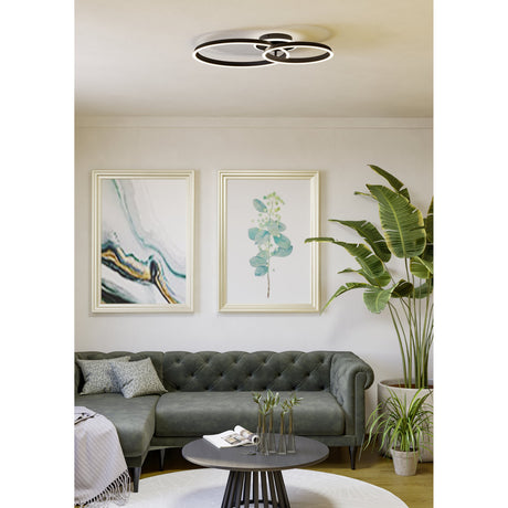 Girifalco LED 2 Ring Flush Ceiling Light in black, two overlapping aluminium and steel rings with diffusers, mounted above a grey sofa and framed art in a living room.