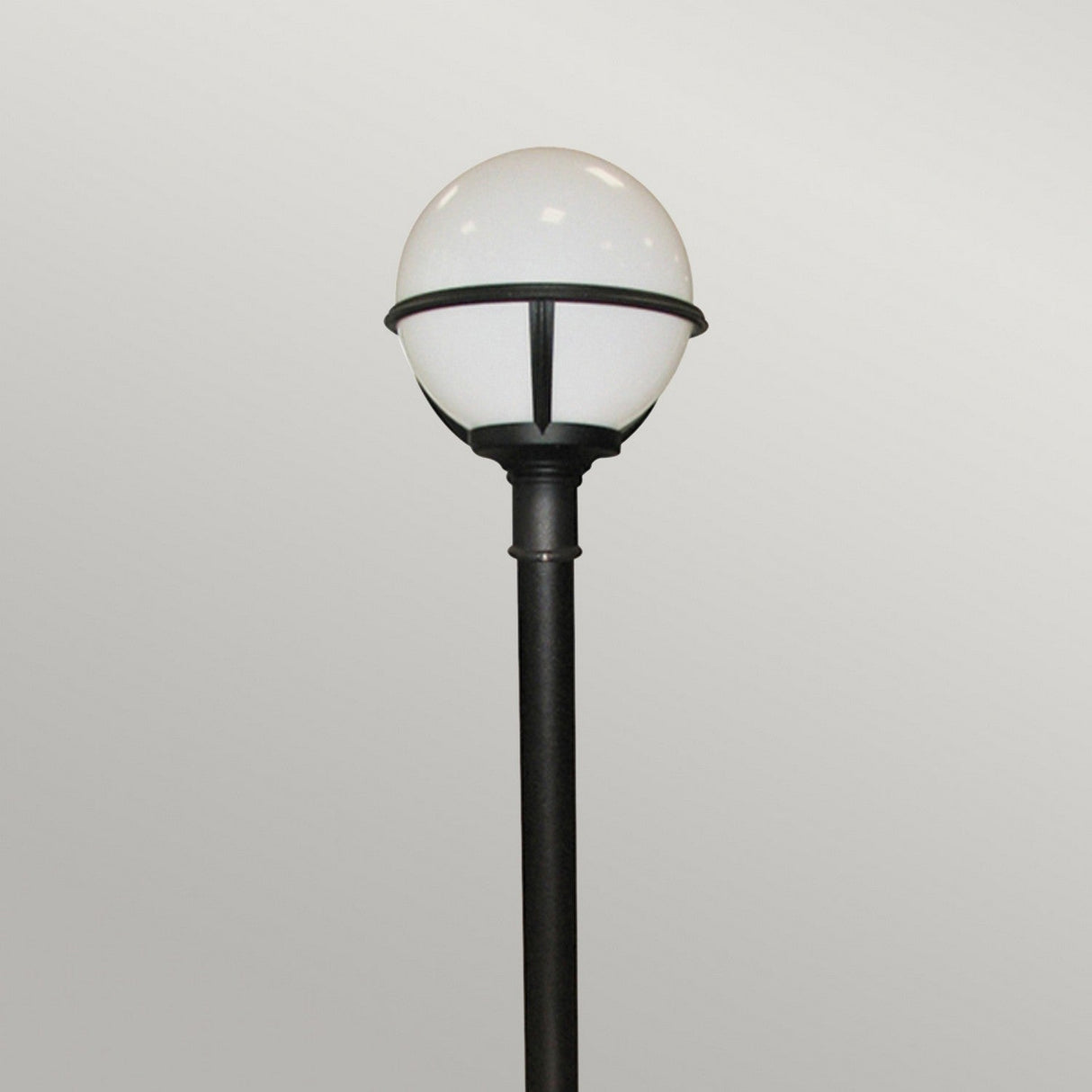 The Glenbeigh 1 Light Pillar Lantern in black, featuring a round, white globe-shaped light fixture, stands against a plain, light gray background, showcasing elegant outdoor lighting. With its IP44 rating and corrosion-proof design, this lantern ensures both style and durability in any setting.